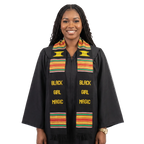 Graduate wearing a Black Girl Magic kente graduation stole with multicolored stripes and fringe over a gold cap and gown.
